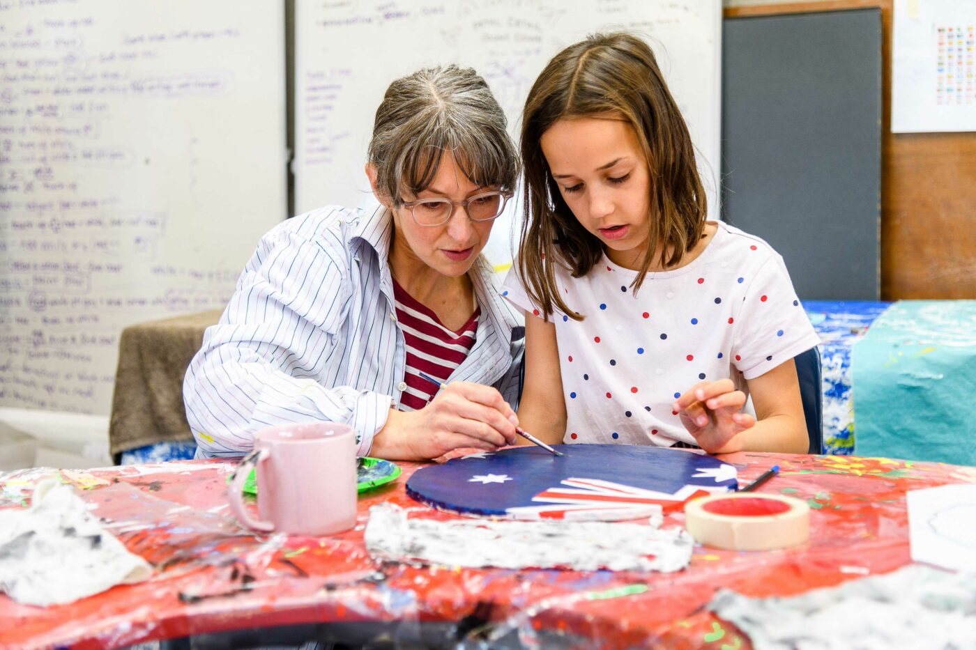 Teacher Aide works on painting with a child.