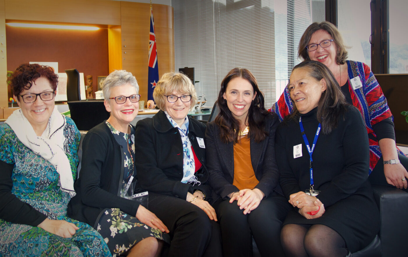 NZEI Te Riu Roa members and staff sitting on a couch with Jacinda Ardern.